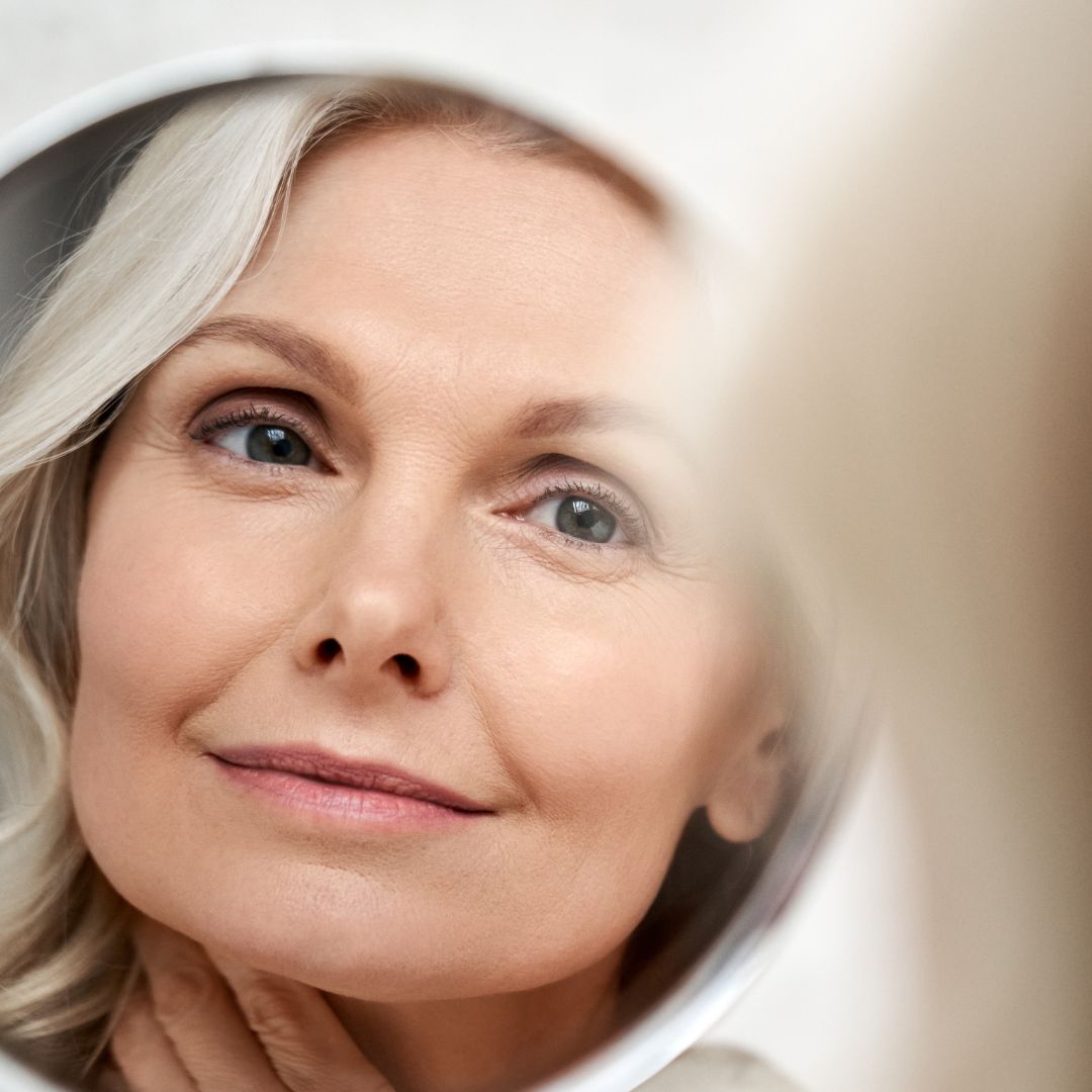 Older woman smiling at herself in the mirror